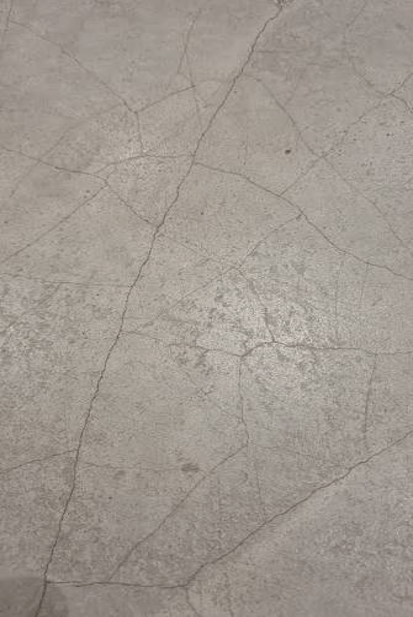Close-up view of a cracked concrete floor with a textured surface.